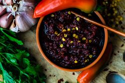 Close up of pot of traditional Georgian sauce Adjika with garlic bulb & raw ingredient