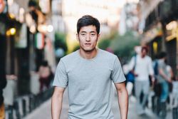 Confident Asian man walking along city street