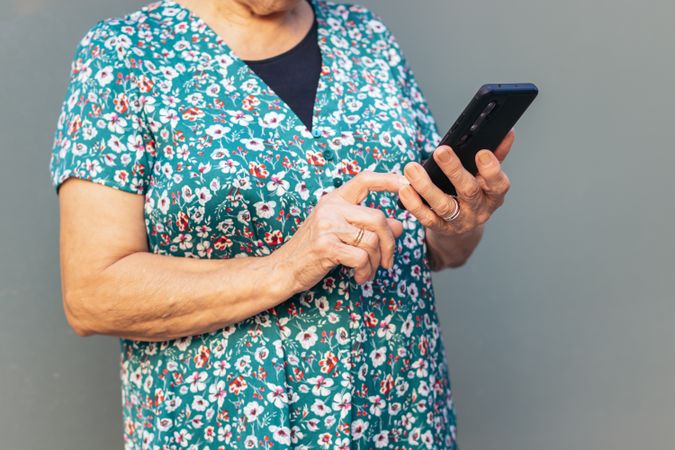 Unrecognizable older woman using smartphone outdoors