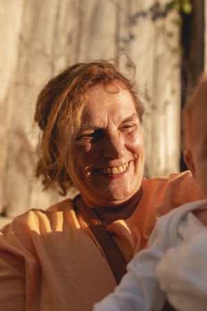 Smiling older woman holding young child on sunny day