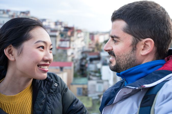 Positive multiethnic resting couple talking while walking at city street