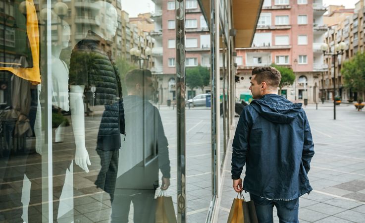 Man with shopping bags in front clothing store