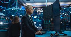 Financial Analyst Using Desktop Computer with Multi-Monitor Workstation with Real-Time Graphs, Financial Reports and Market Charts.