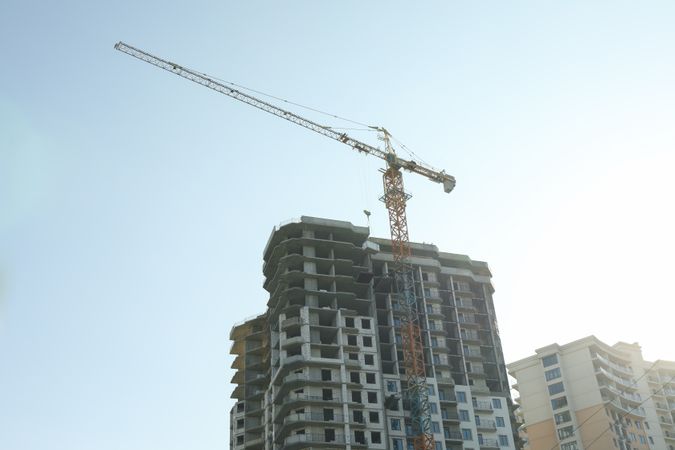 High-rise construction with crane against blue sky