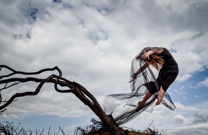 Woman posing in air near dry twigs and blue sky