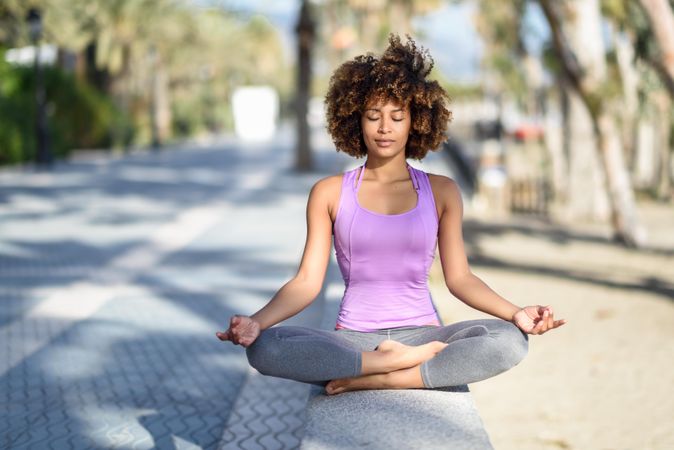 Black woman with afro hairstyle meditating near the beach