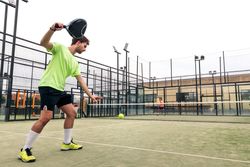 Young man serving in a paddle tennis game