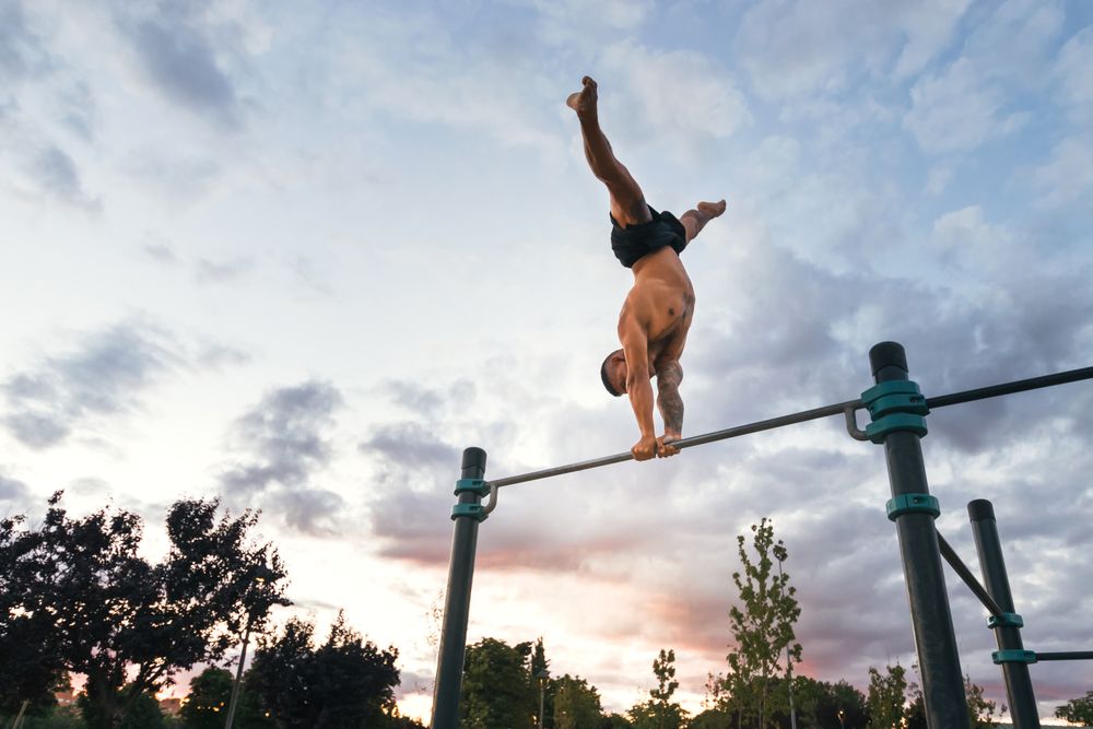 male athlete doing handstand on a bar in a calisthenic park