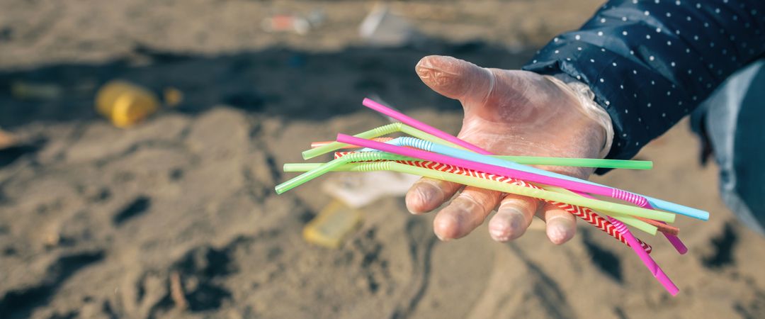 Woman showing handful of straws collected on the beach