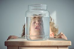 Sleepy boy reflection in glass bottle with water