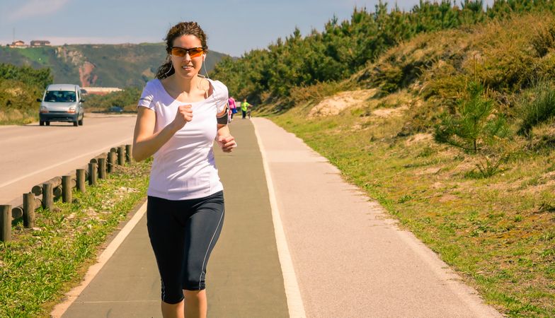 Woman in athletic gear jogging along road