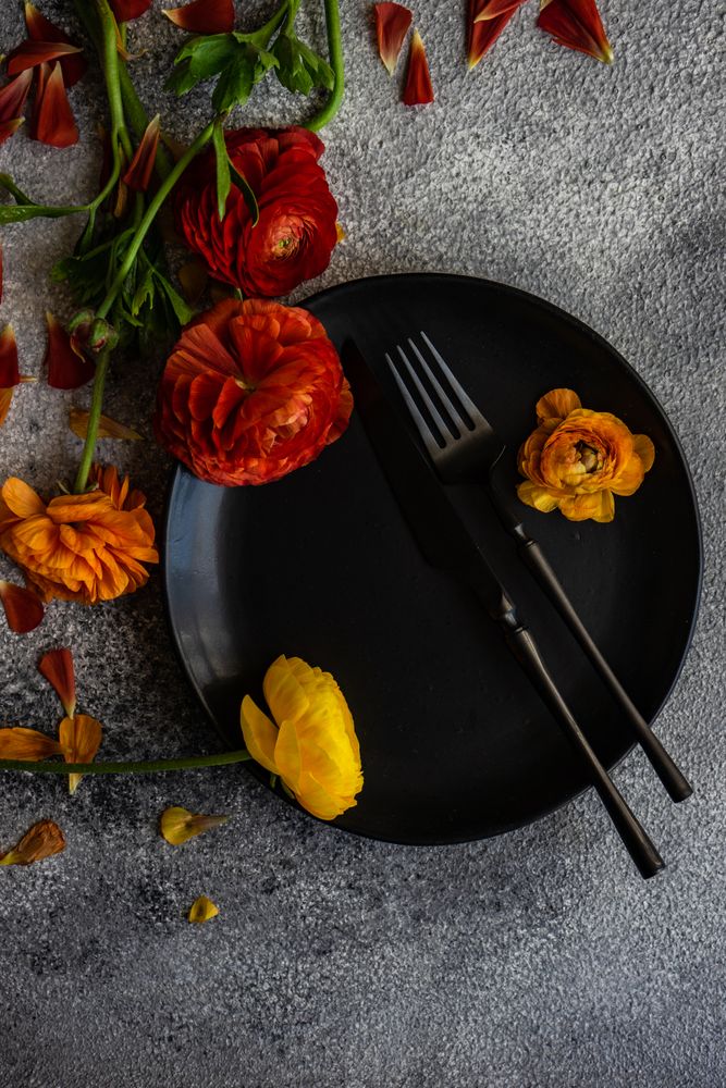 Rustic table setting with dark plate and fresh flowers