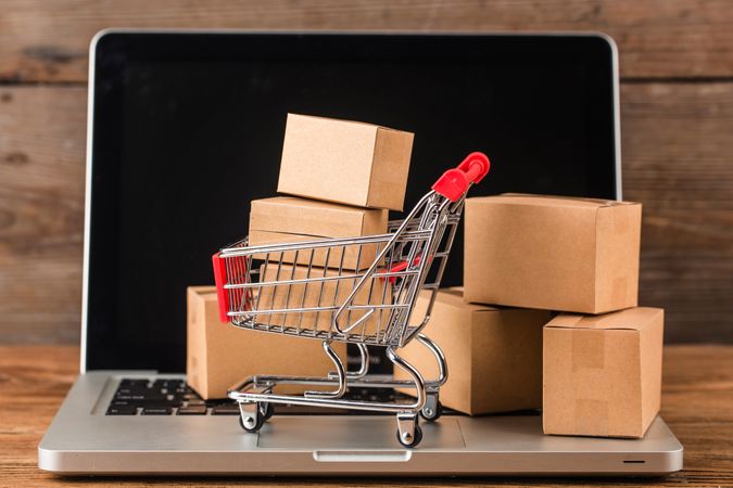 Miniature Shopping Cart on Laptop Representing Online Shopping and Delivery Concept