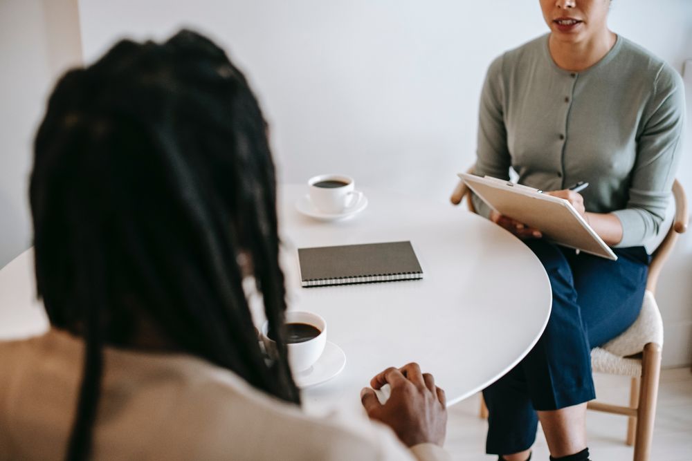 Cropped image of woman taking notes while having a coffee with a person