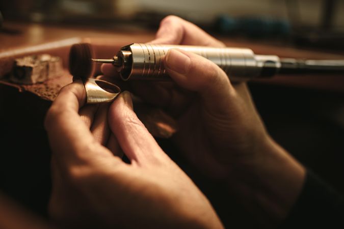 Hands of woman jeweler polishing a ring surface with grinding machine