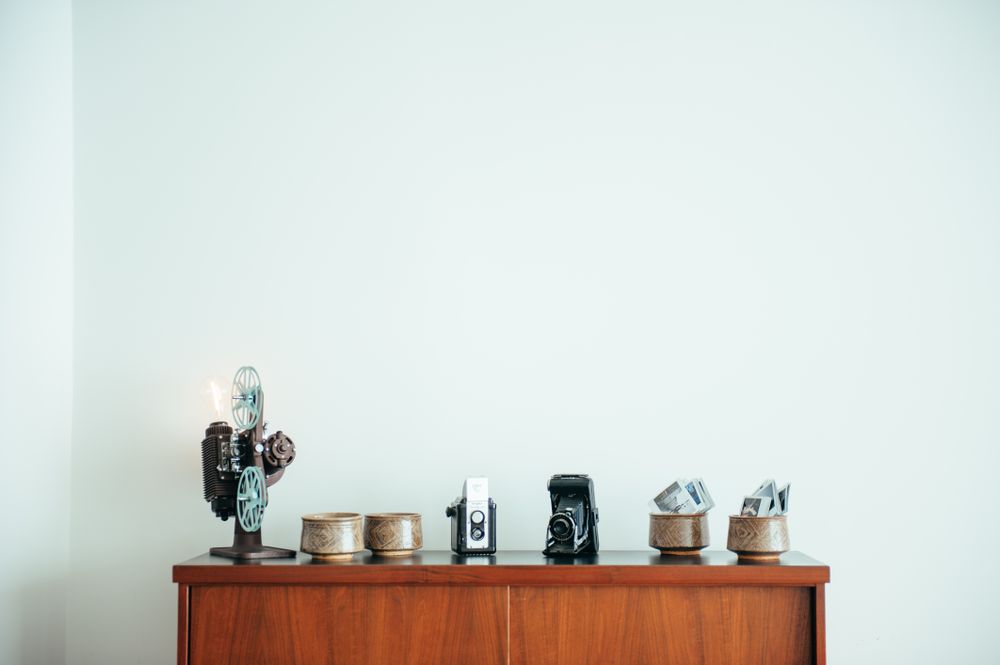 Top of bookshelf with row of vintage cameras and ceramic pots