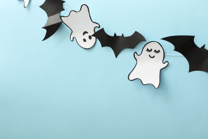 Paper ghosts and bats on blue background, space for text
