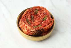 Brass pot of kimchi on marble table