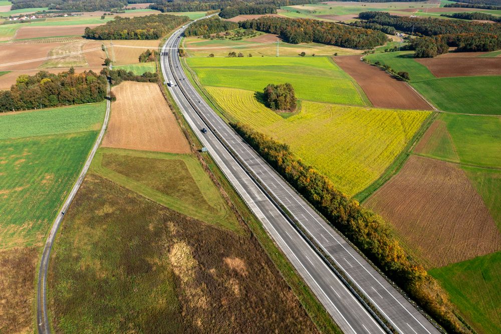 Aerial view of a two-lane highway passing through autumn nature in Germany