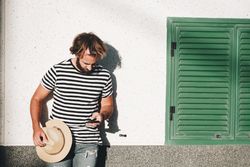Young male leaning on wall with smartphone
