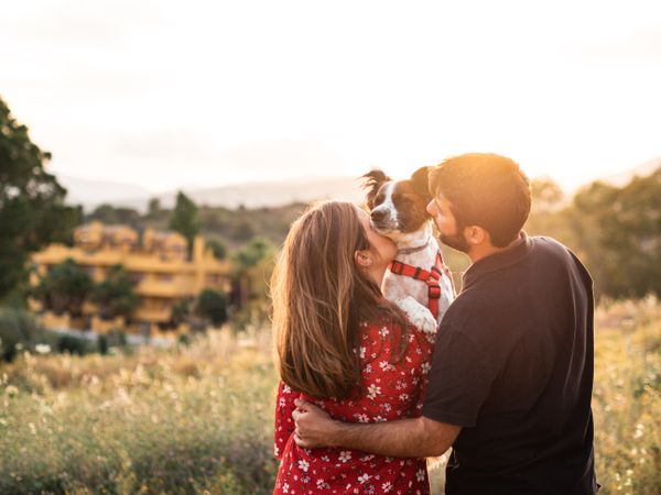 Happy couple with friendly cute dog outdoors