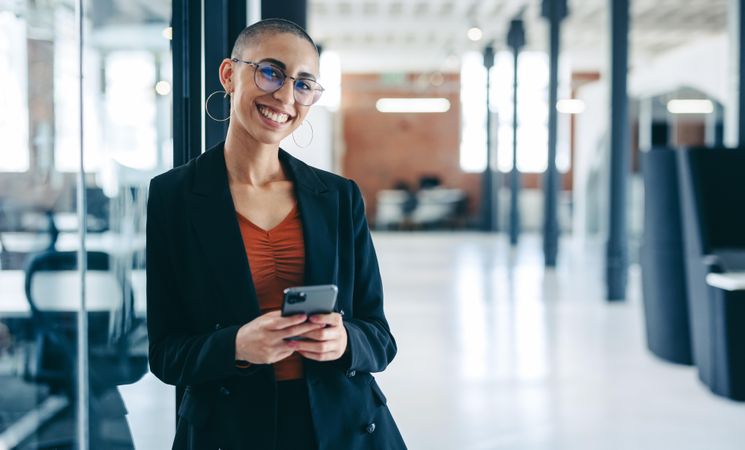 Portrait of confident businesswoman smiling at the camera while holding a smartphone