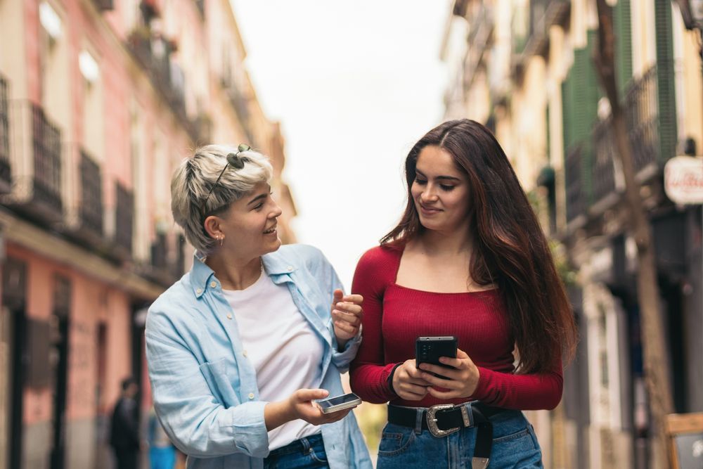 two women walking and using her mobiles