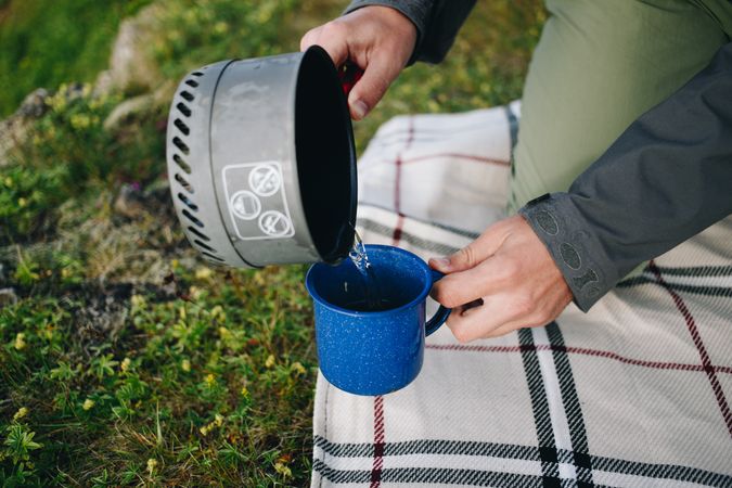 Person pouring coffee at campsite