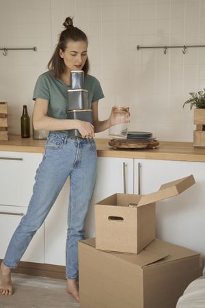 Careful woman holding containers with hand and taking cans out of box