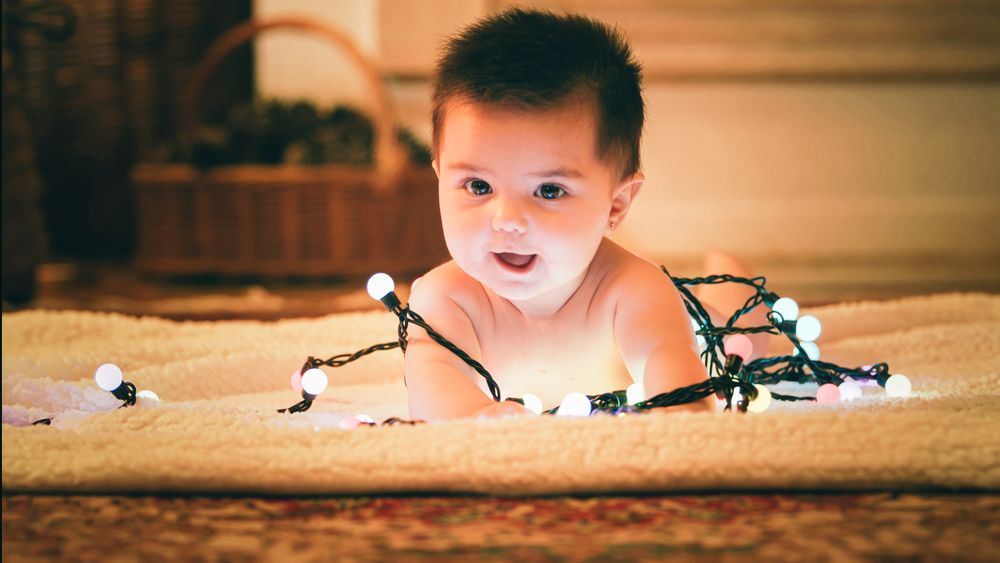 Baby playing with light garland on Christmas Day