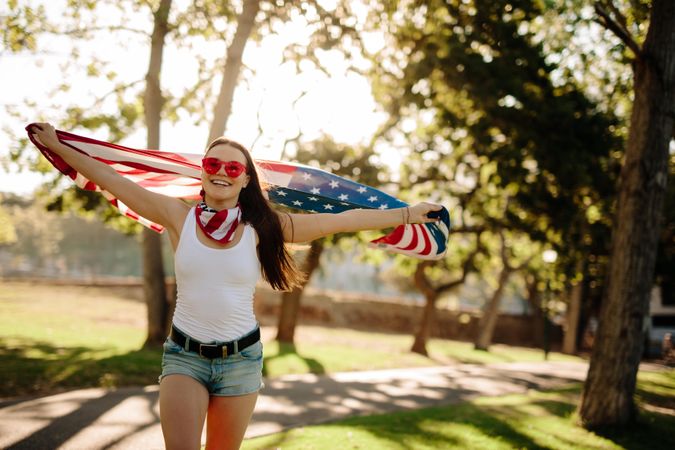 Female in park with USA flag in hands celebrating independence day