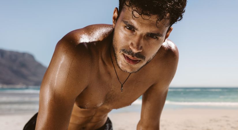 Attractive man after exhausting workout on a beach