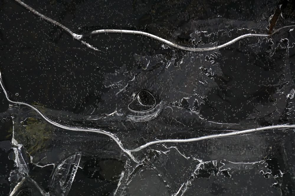 Fragment of thin ice on dark frozen river