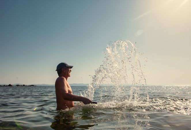 Man swimming and splashing water in sunlight