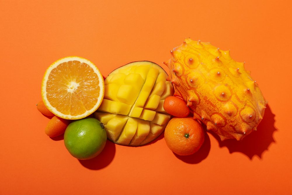 Set of tropical fruit on orange background, top view