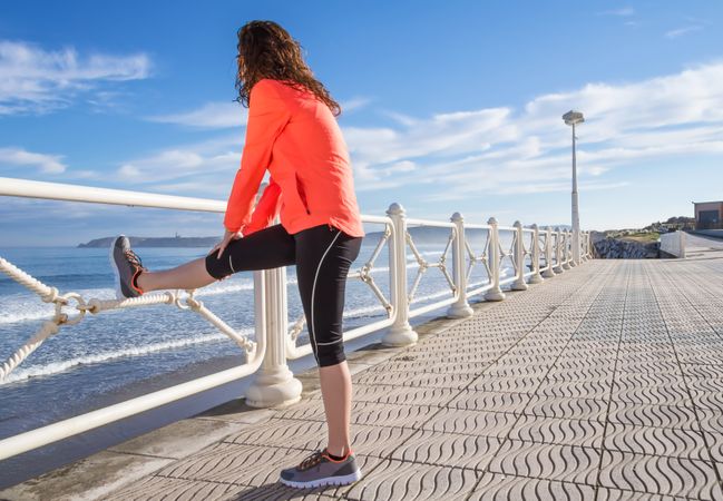 Athletic woman stretching before running on the beach promenade on a summer morning