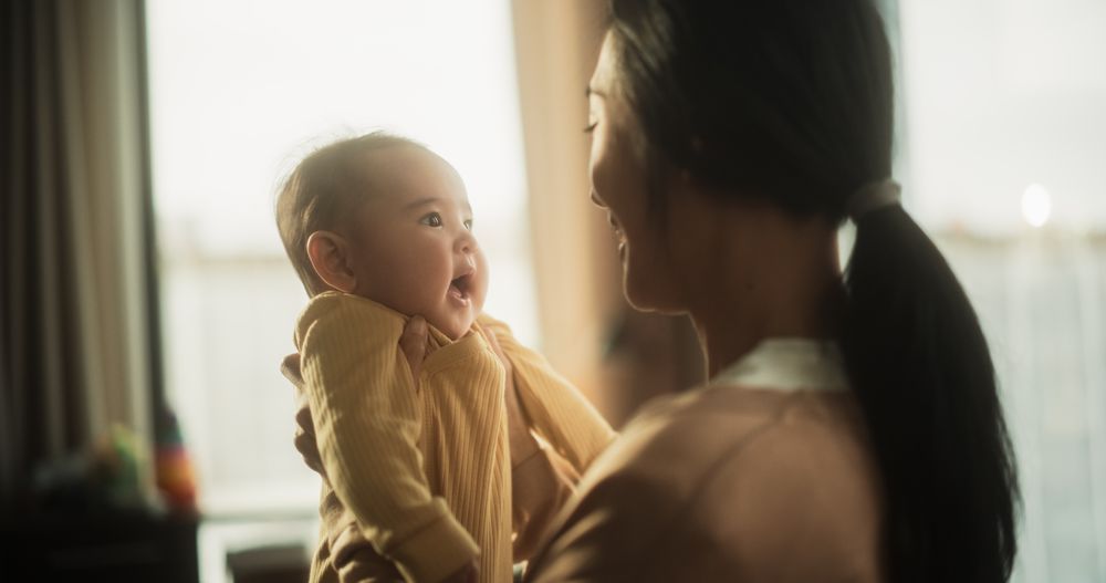 Motherly Affection Concept: Portrait of a Cute Asian Baby Laughing.