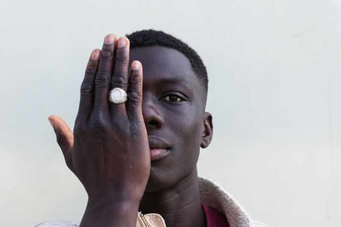 Stylish Black man covering face and looking at camera