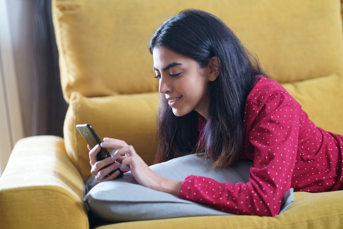 Woman relaxing at home while reading on a smart phone