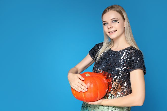 A woman in a Halloween costume with a pumpkin in her hands
