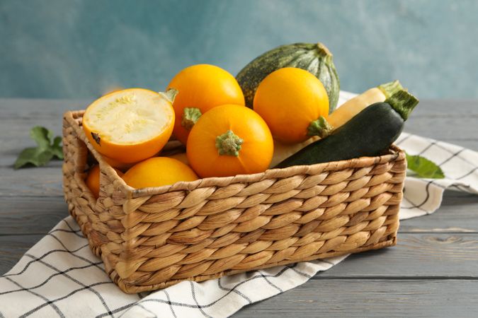Basket with zucchini on napkin on wooden table