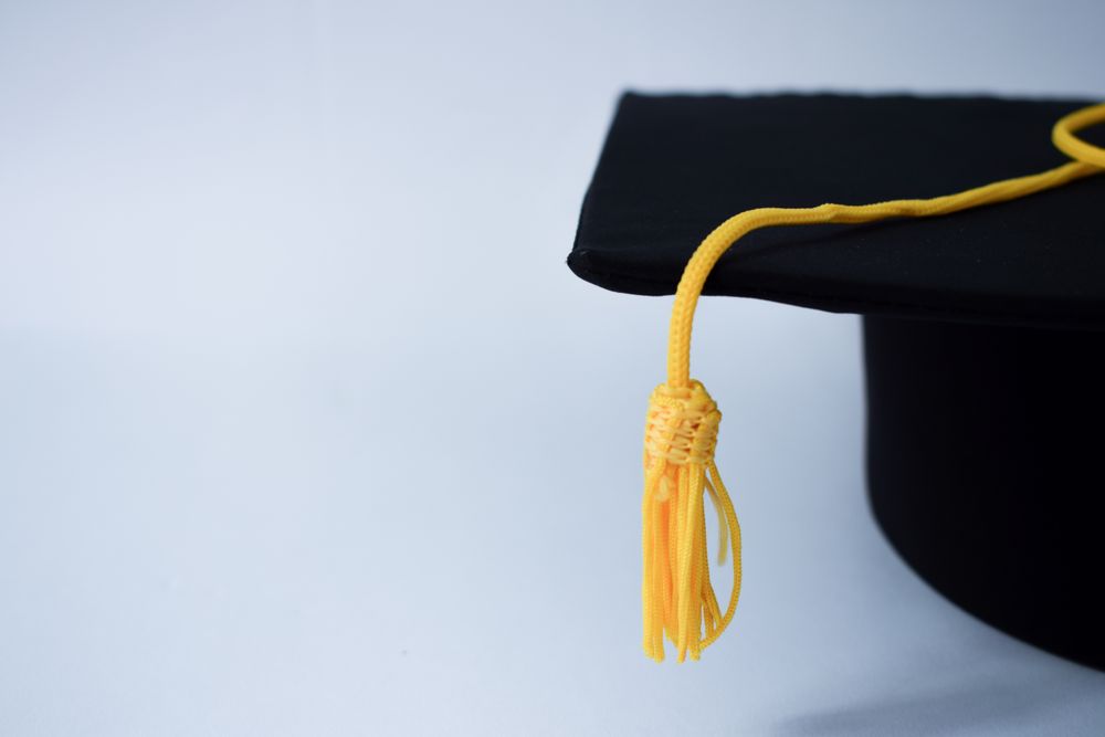 Graduation cap & yellow tassel in studio shoot with copy space