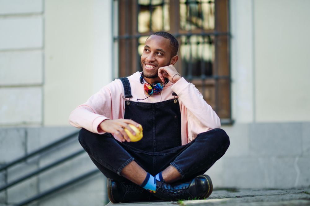 Calm male in overalls and boots sitting cross legged on outdoor steps