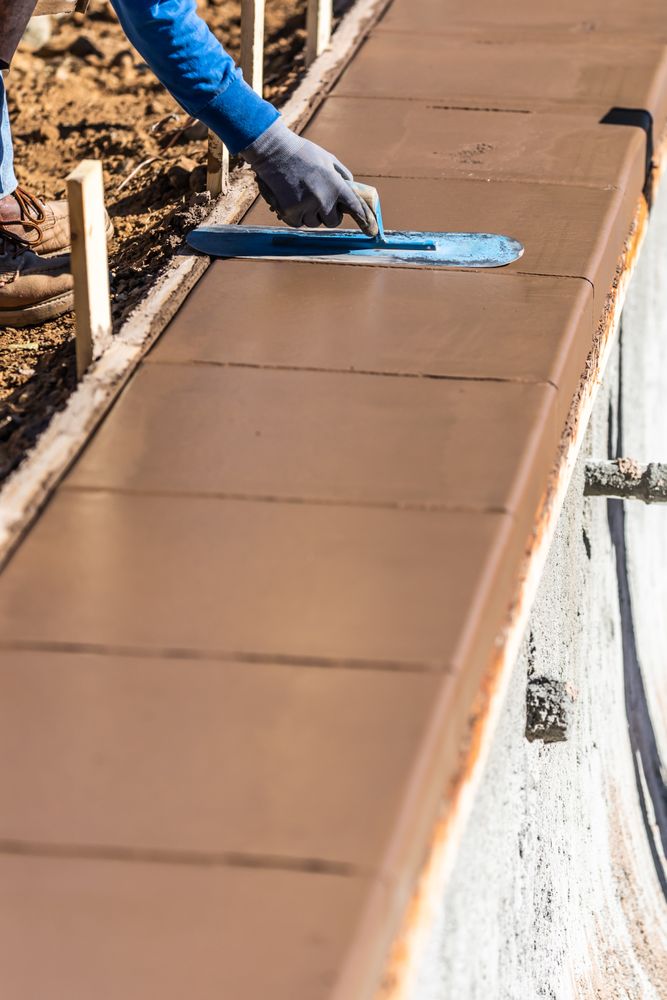 Construction Worker Using Trowel On Wet Cement Forming Coping Around New Pool