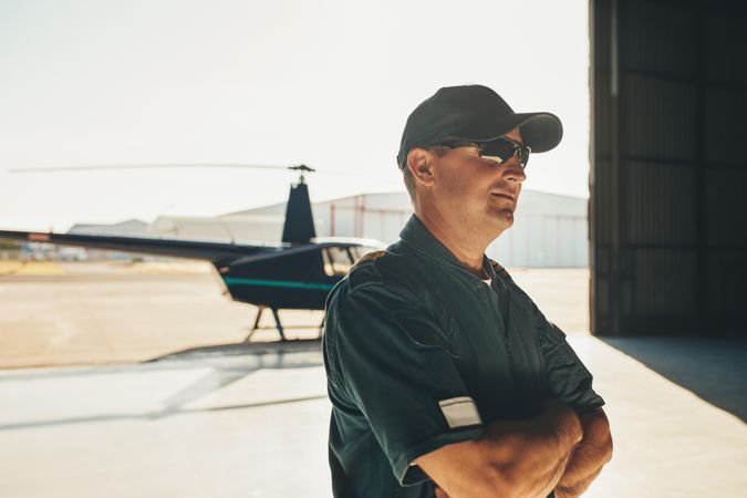 Proud man with arms crossed in front of helicopter