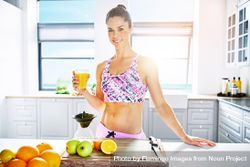 Muscular fit woman with fresh fruit juice in bright kitchen bYDQj4