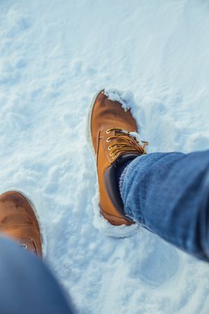 Man legs in winter boots on snow near mountains