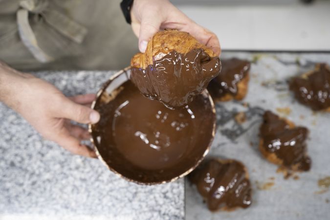 Confectioner decorating freshly baked croissants