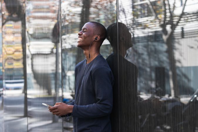 Black man listening to music in earphones on smartphone