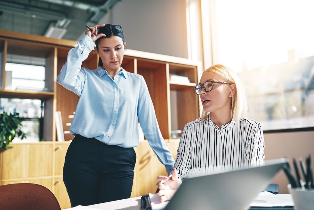 Two women discussing work in a bright modern office
